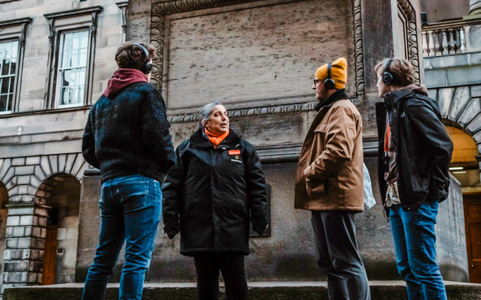 Tour guide leading a group on the Royal Mile in Edinburgh, near historic buildings.