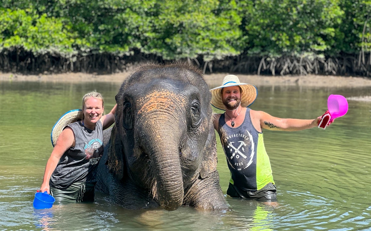 Visitors interacting with an elephant in water at Krabi Elephant Shelter.