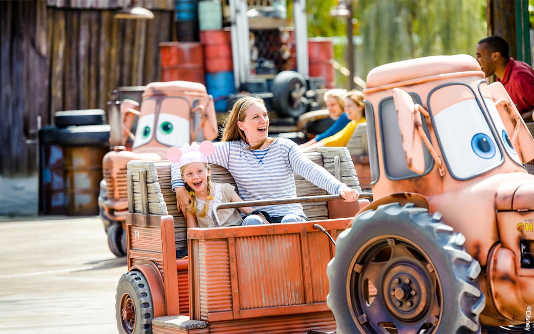 Family enjoying Mater's Junkyard Jamboree ride at Cars Land, Disneyland Adventure Park, California.