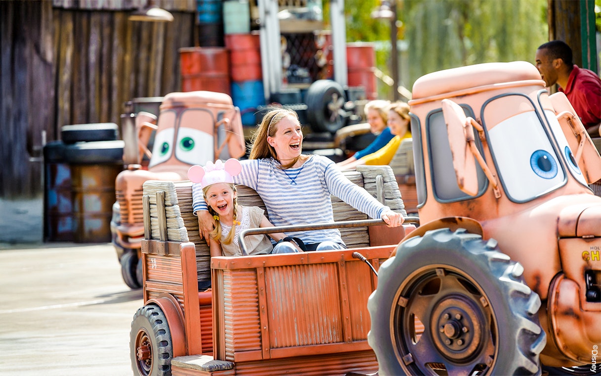 Family enjoying Mater's Junkyard Jamboree ride at Cars Land, Disneyland Adventure Park, California.