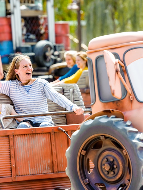 Family enjoying Mater's Junkyard Jamboree ride at Cars Land, Disneyland Adventure Park, California.