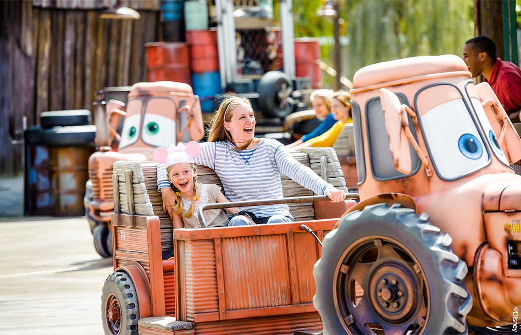 Family enjoying Mater's Junkyard Jamboree ride at Cars Land, Disneyland Adventure Park, California.