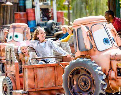 Family enjoying Mater's Junkyard Jamboree ride at Cars Land, Disneyland Adventure Park, California.
