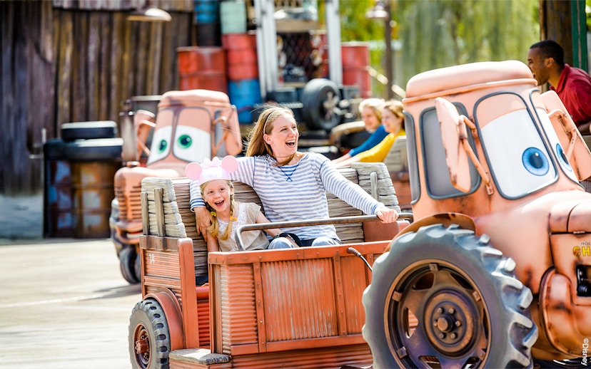 Family enjoying Mater's Junkyard Jamboree ride at Cars Land, Disneyland Adventure Park, California.