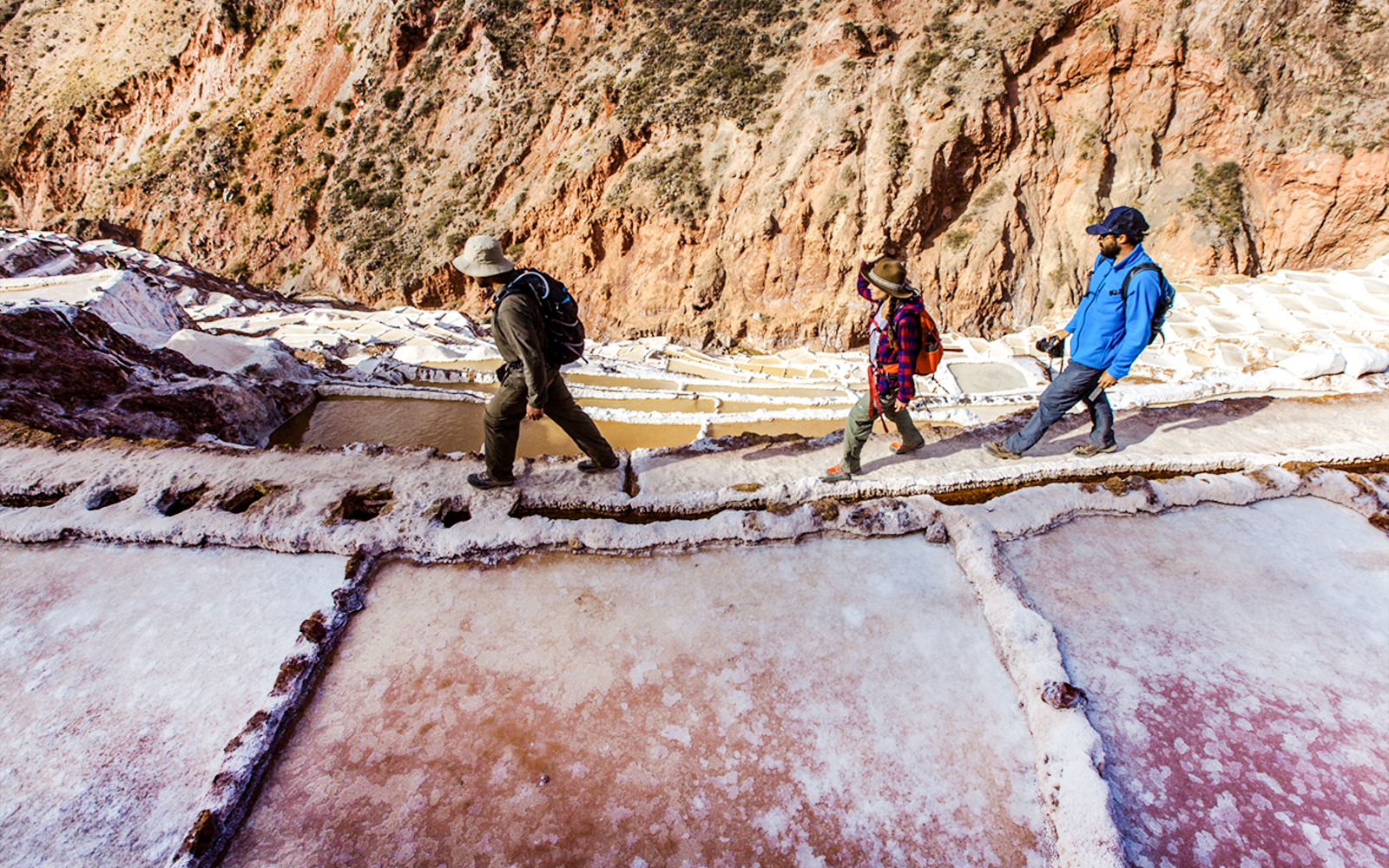 Visitors walking along the Maras Salt Mines terraces in the Sacred Valley, Peru.