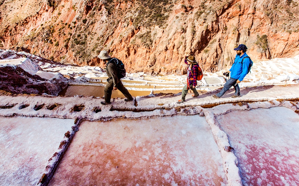 Visitors walking along the Maras Salt Mines terraces in the Sacred Valley, Peru.