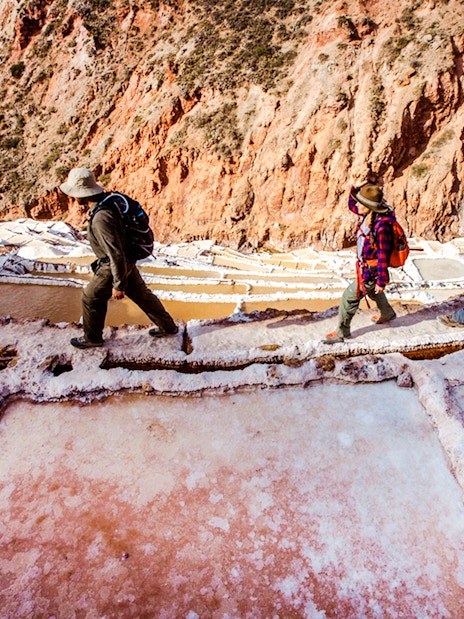 Visitors walking along the Maras Salt Mines terraces in the Sacred Valley, Peru.