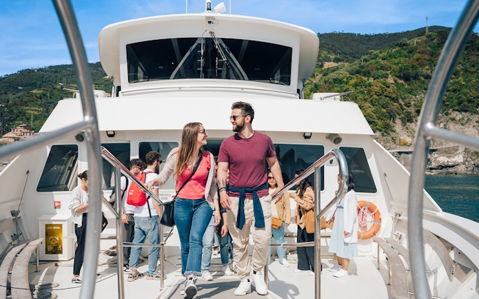 Couple on a boat during Cinque Terre day trip from Florence, with coastal scenery in the background.