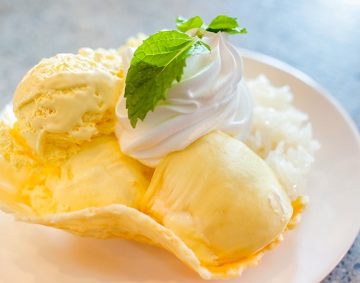 Durian ice cream with whipped cream and mint on a white plate.