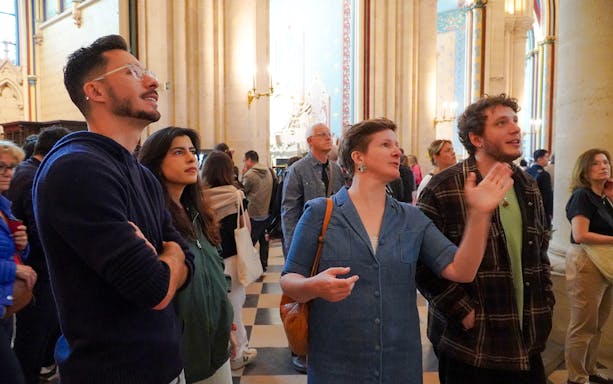 Guide explaining Notre Dame's interior to tourists.