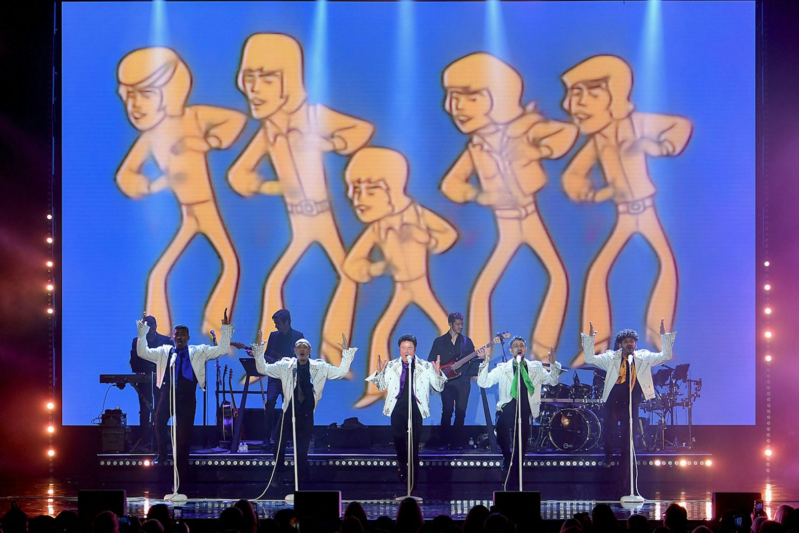 Performers on stage with animated figures in the background during a Donny Osmond show.