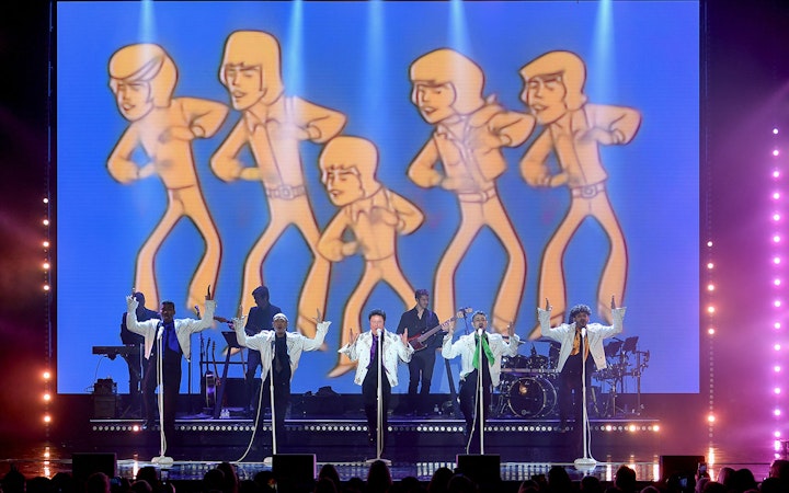 Performers on stage with animated figures in the background during a Donny Osmond show.