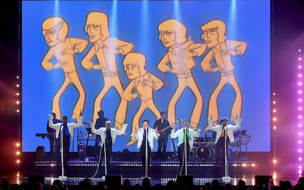 Performers on stage with animated figures in the background during a Donny Osmond show.