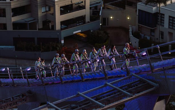 Group climbing Story Bridge in Brisbane during twilight.