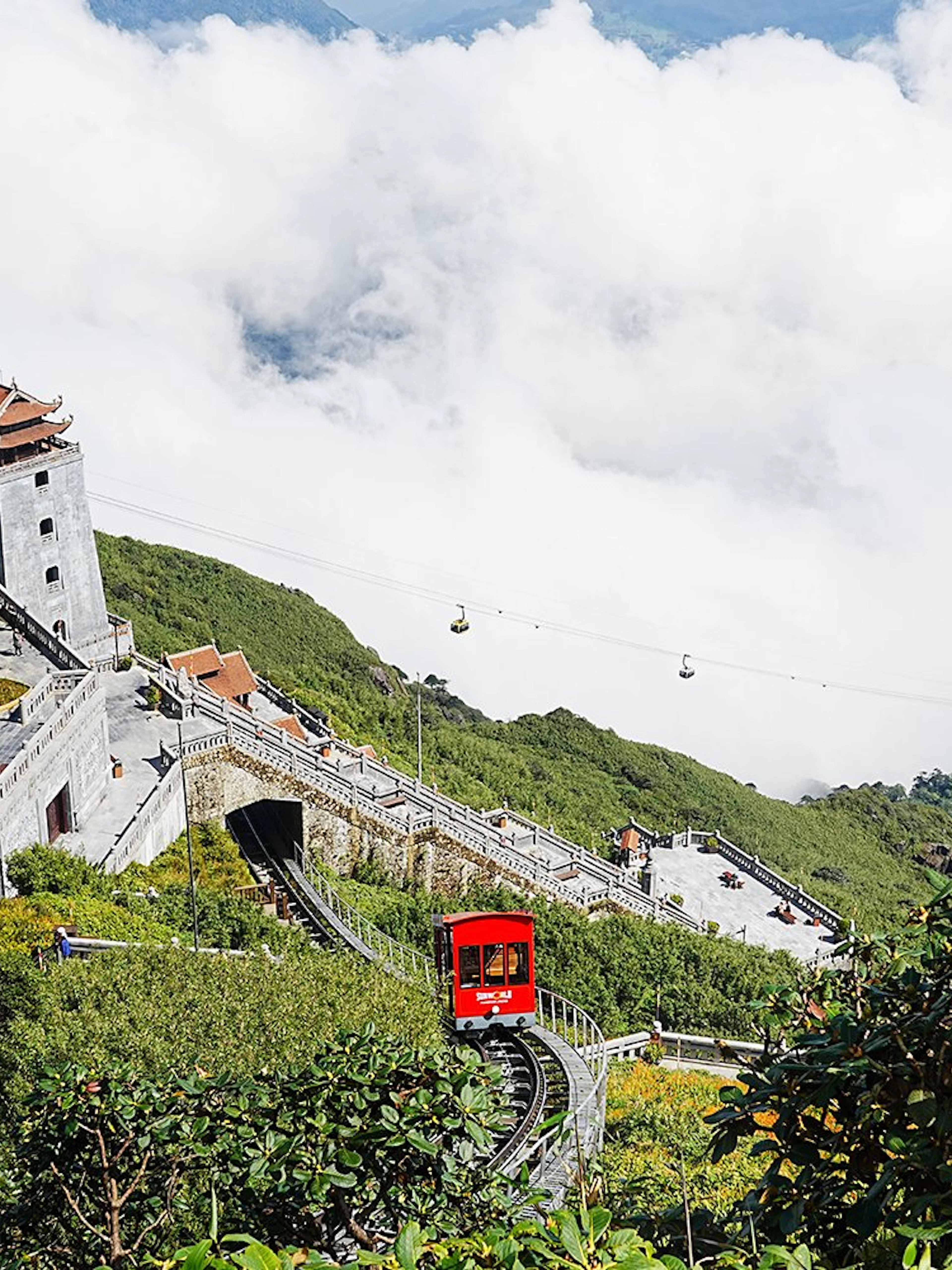 Buddha statue and cable car at Sun World Fansipan, Vietnam, surrounded by clouds and greenery.