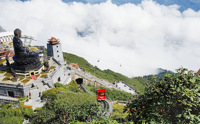 Buddha statue and cable car at Sun World Fansipan, Vietnam, surrounded by clouds and greenery.