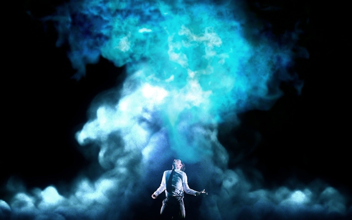 Person standing under blue smoke, evoking a supernatural atmosphere.