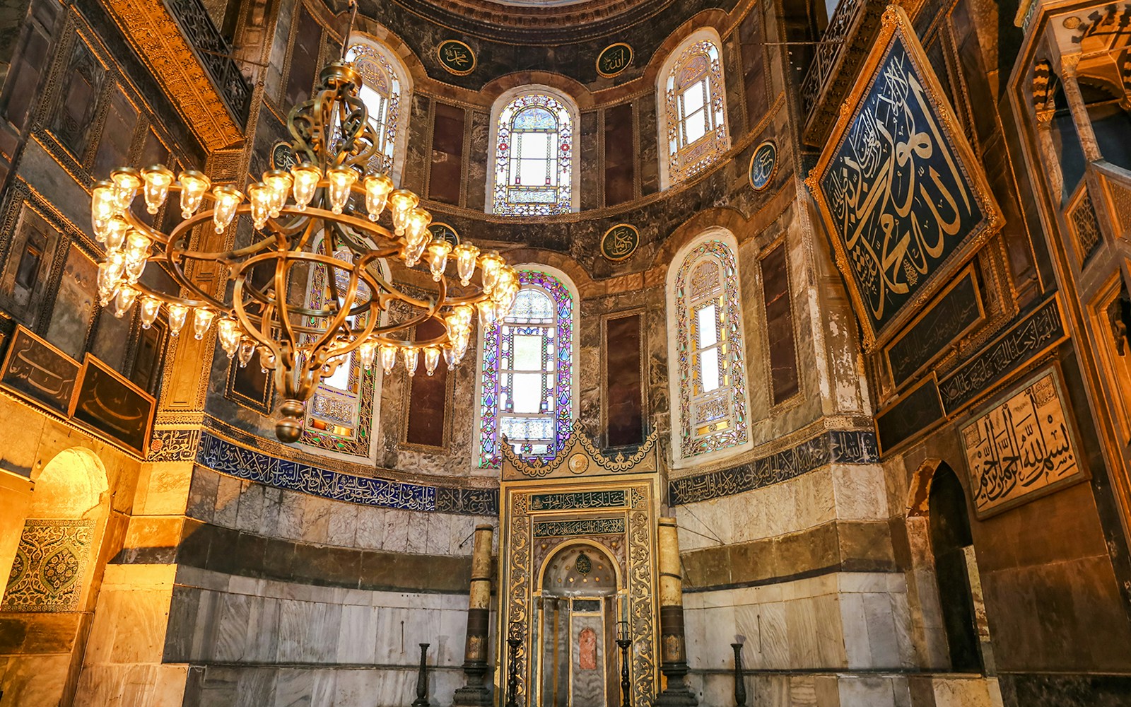 Interior view of Hagia Sophia in Istanbul, featuring ornate chandeliers and intricate stained glass windows.
