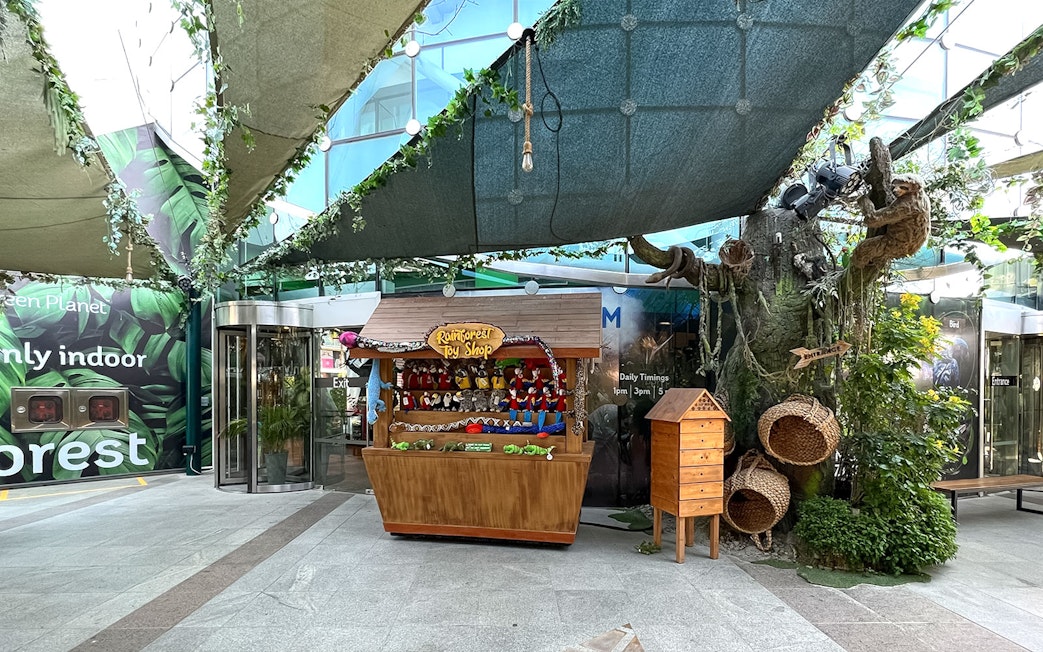 Rainforest toy shop and tree display at Green Planet Dubai entrance.