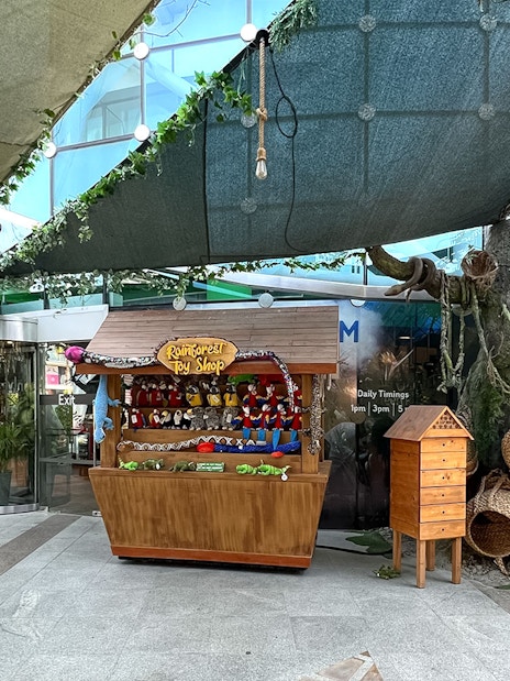 Rainforest toy shop and tree display at Green Planet Dubai entrance.