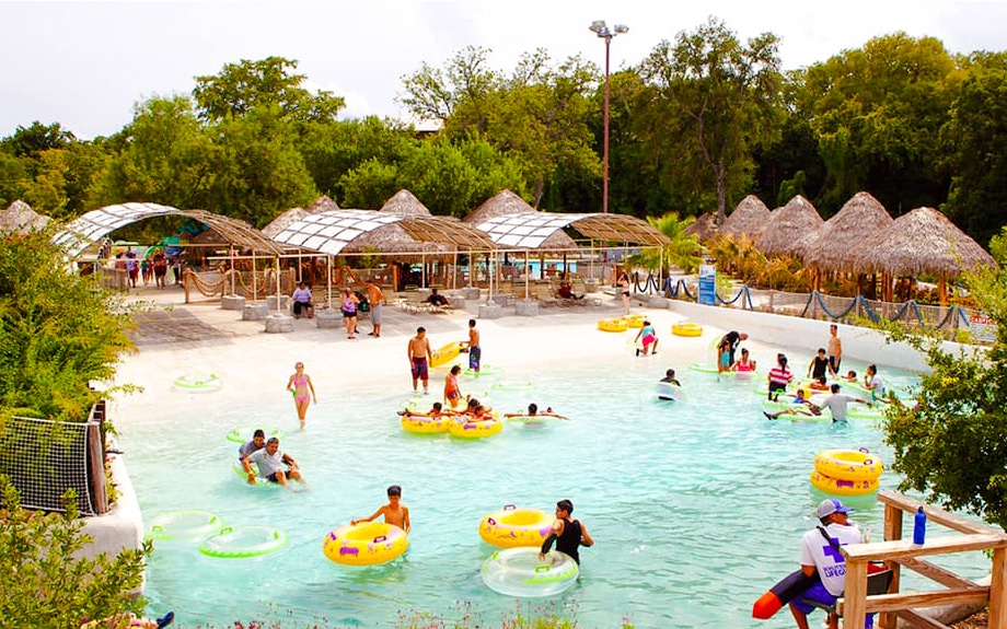 Visitors enjoying the wave pool at Schlitterbahn New Braunfels, surrounded by lush greenery.