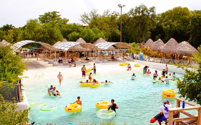 Visitors enjoying the wave pool at Schlitterbahn New Braunfels, surrounded by lush greenery.