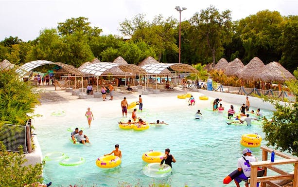 Visitors enjoying the wave pool at Schlitterbahn New Braunfels, surrounded by lush greenery.