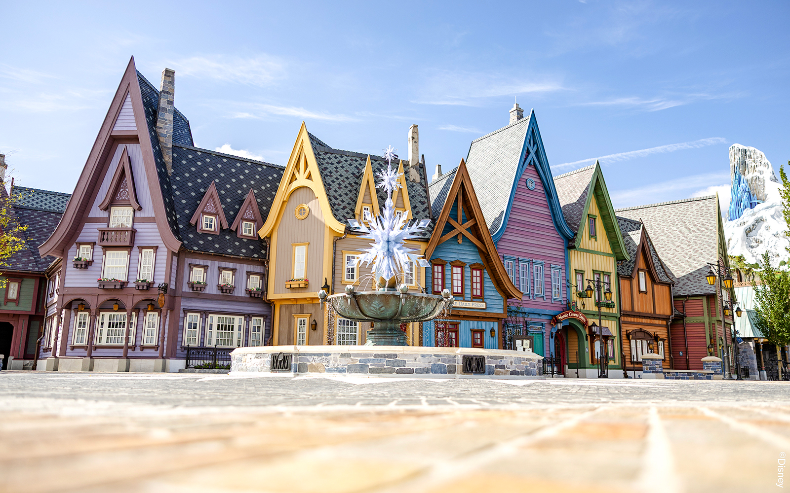 Colorful Arendelle village buildings with snowflake fountain at Disneyland World of Frozen.