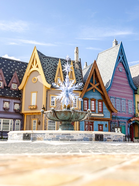 Colorful Arendelle village buildings with snowflake fountain at Disneyland World of Frozen.