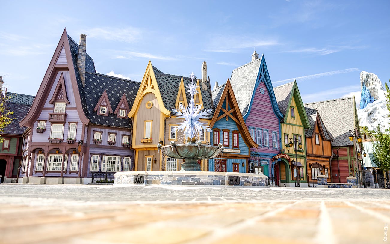 Colorful Arendelle village buildings with snowflake fountain at Disneyland World of Frozen.