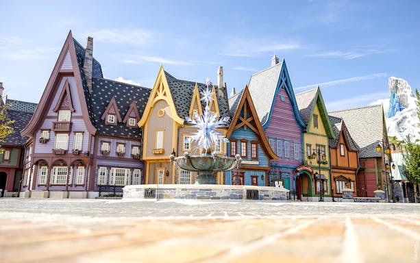 Colorful Arendelle village buildings with snowflake fountain at Disneyland World of Frozen.