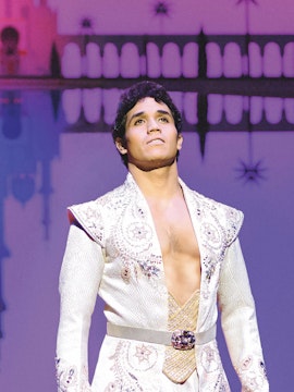 Performer in ornate costume on stage during a classic theater production.