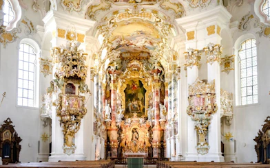 Ornate interior of chapel inside Neuschwanstein Castle, featuring intricate gold and white designs.
