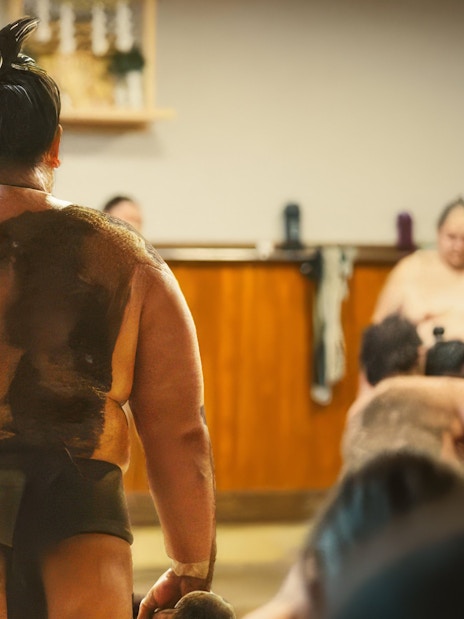 Sumo wrestler preparing for a match in a traditional Japanese dojo.