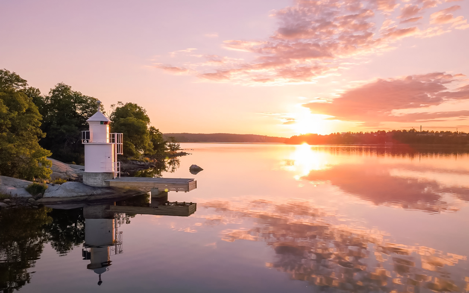 Lighthouse on Stockholm Archipelago reflecting in water at sunset.