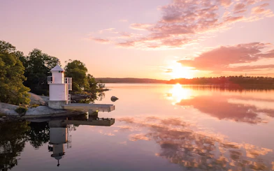 Lighthouse on Stockholm Archipelago reflecting in water at sunset.