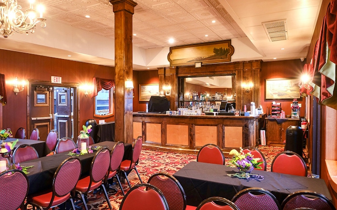Dining area with tables and chairs, warm lighting, and a bar in Steamboat Natchez.