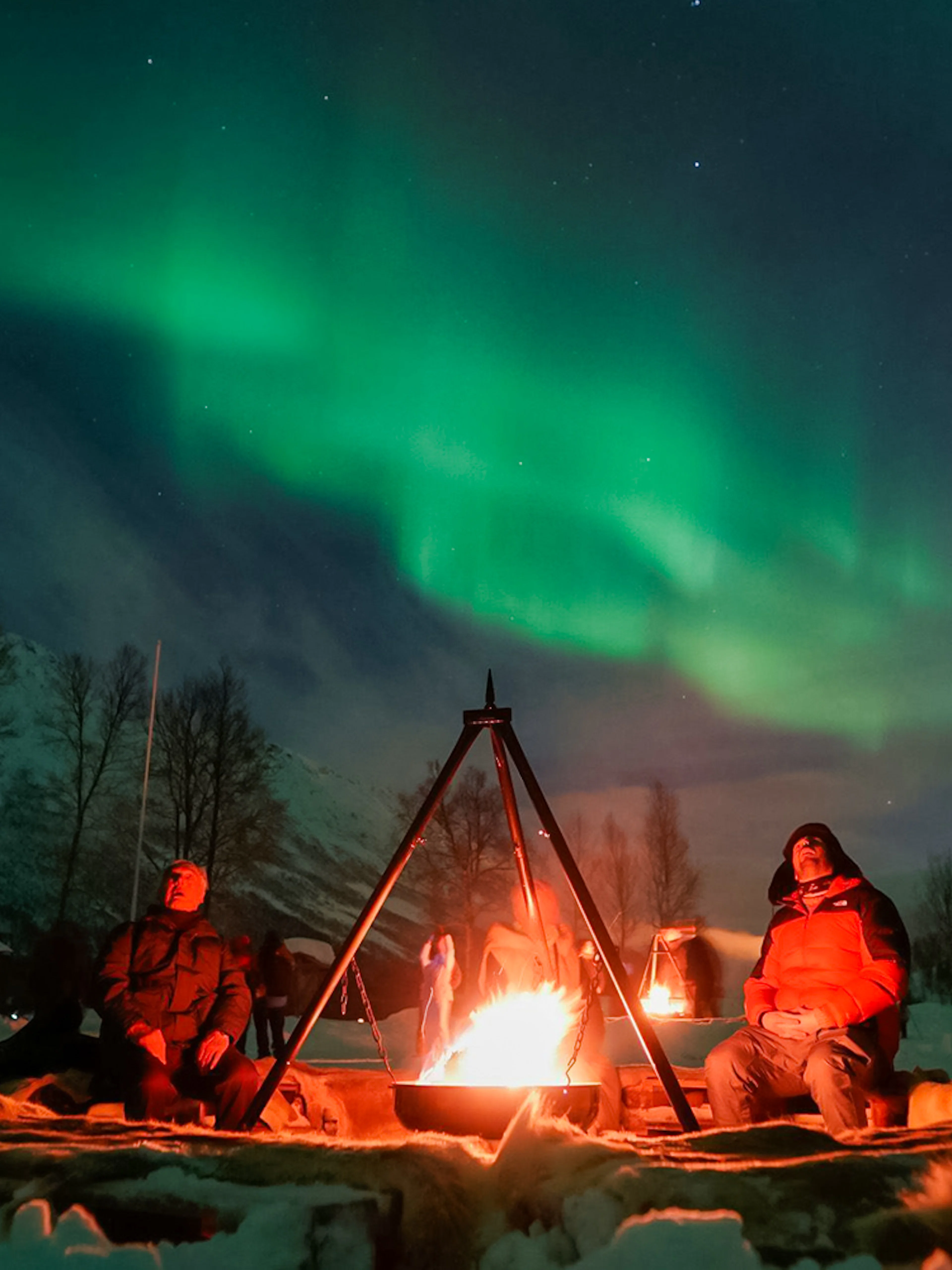 Campfire under Northern Lights at a safari camp in Tromsø.