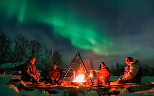 Campfire under Northern Lights at a safari camp in Tromsø.