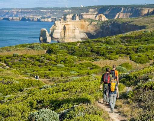 Hikers on a trail overlooking the scenic coastline of the Great Ocean Road, Australia.
