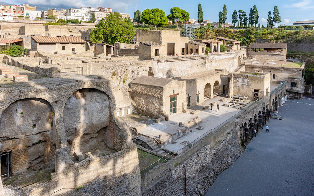 Ruins of Herculaneum entrance with ancient stone structures and arches, Italy.