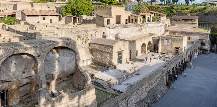 Ruins of Herculaneum entrance with ancient stone structures and arches, Italy.
