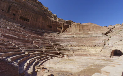 Ancient Nabataean Theater with stone seating in Petra, Jordan under clear blue sky.