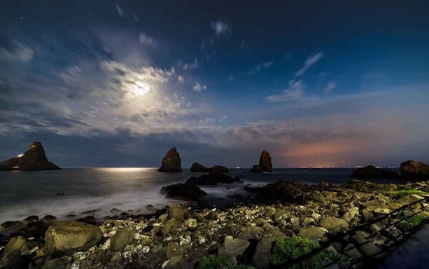 Rocks and sea stacks at night along the Riviera of the Cyclops, viewed from Catania.