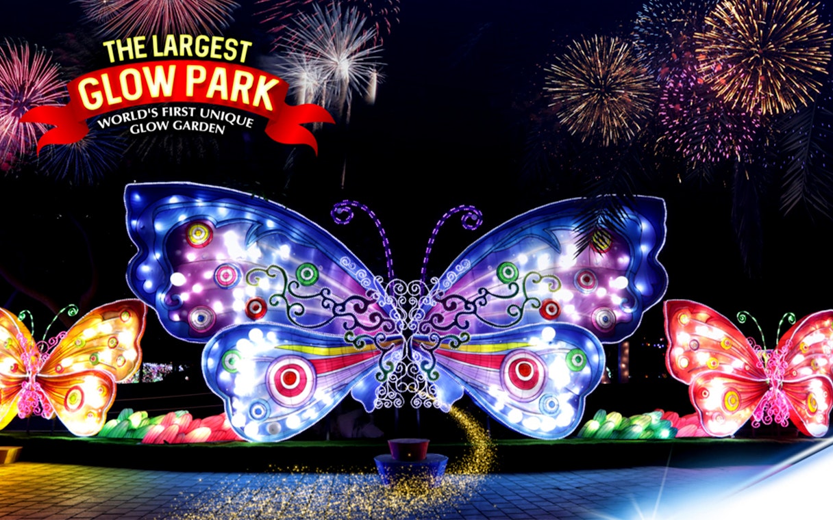Illuminated butterfly sculptures at Dubai Garden Glow with fireworks in the background.