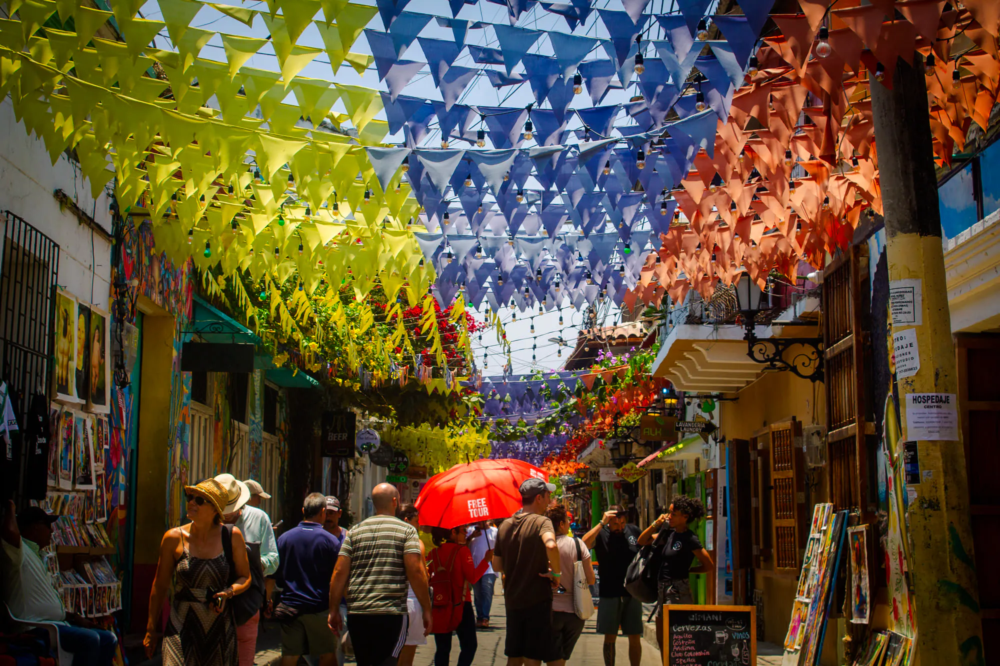 Street in Cartagena's Walled Old City with colorful flags and tourists exploring.