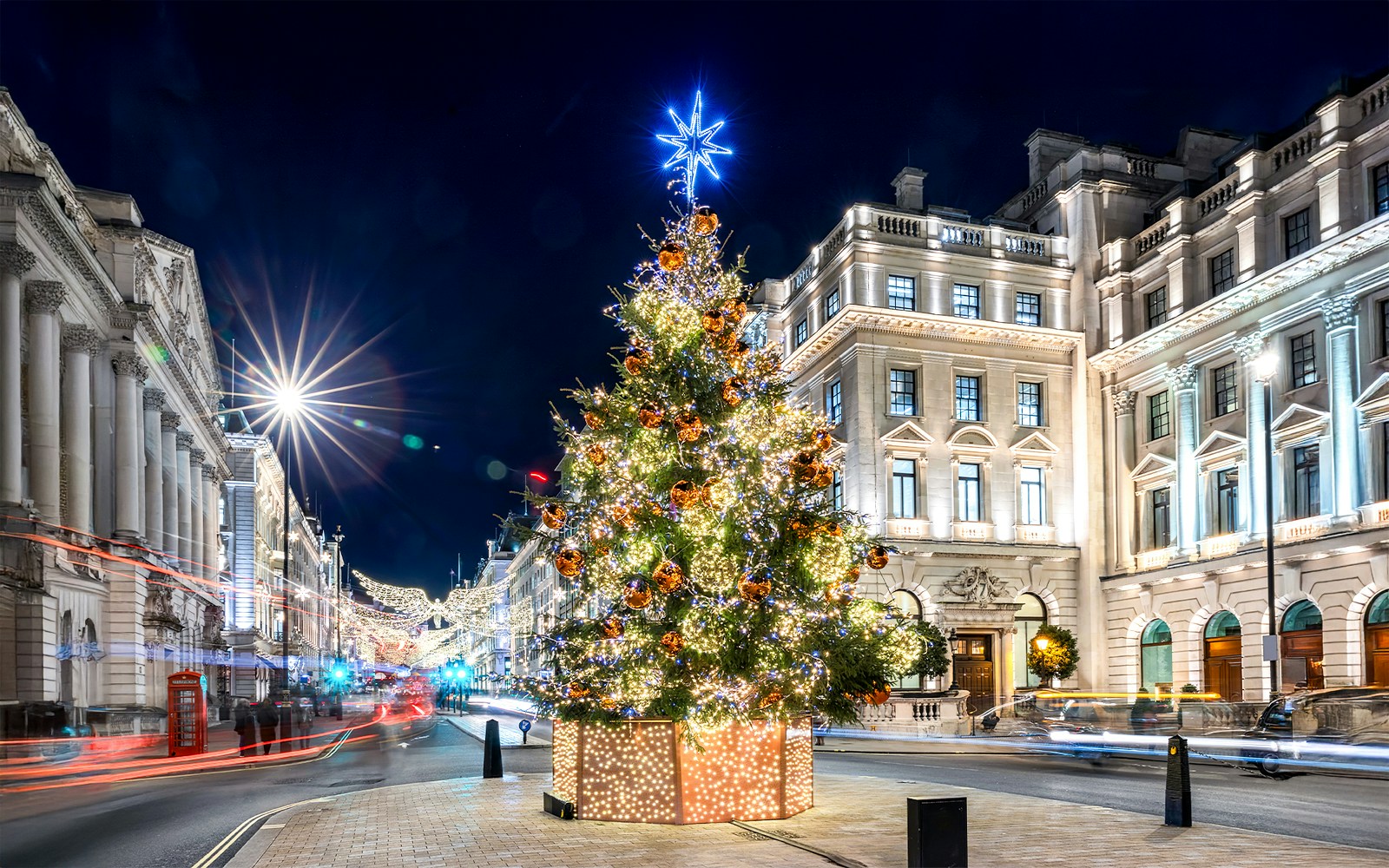 Festive Christmas tree with lights in central London street at night.