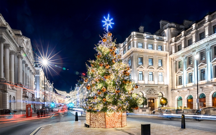 Festive Christmas tree with lights in central London street at night.