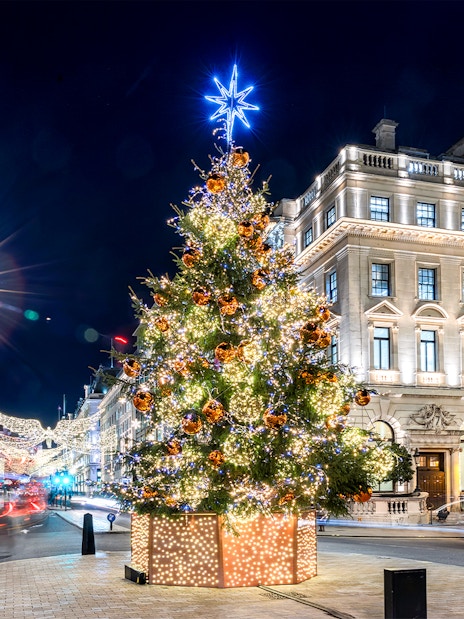Festive Christmas tree with lights in central London street at night.