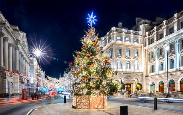 Festive Christmas tree with lights in central London street at night.